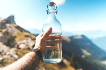 bien s'hydrater avec une bouteille d'eau en verre au sommet de la montagne