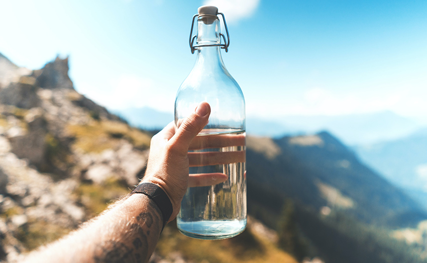 bien s'hydrater avec une bouteille d'eau en verre au sommet de la montagne