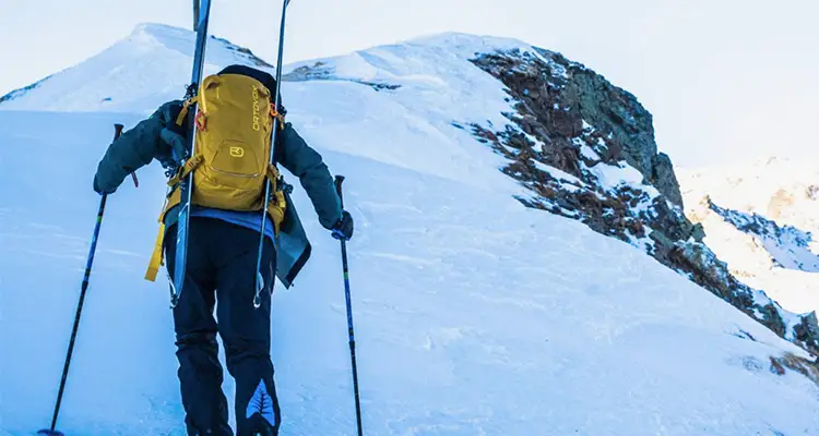 un skieur remontant la montagne à pied